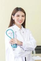Hermosa mujer asiática doctora de pie con los brazos cruzados feliz y sonriendo en el hospital. vistiendo una túnica blanca y un estetoscopio foto