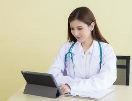 Asian woman doctor searching information about patient on her tablet photo