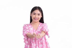 Asian woman in pink dress shows her hand to present something on white background. photo