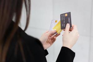 mujer con traje formal negro tiene tarjetas de crédito en sus manos. ella estaba eligiendo tarjetas de crédito para usar su concepto financiero. foto