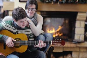 Young romantic couple sitting and relaxing in front of fireplace at home photo