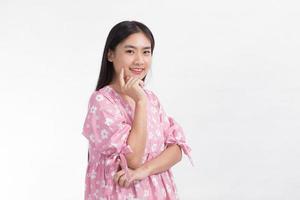 Asian beautiful lady in pink dress and black long hair. Her hands touch cheek, smile, show beautiful skin on white background. photo