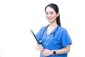 una hermosa doctora asiática de pie sonriendo con una camisa azul de laboratorio, sosteniendo documentos de pacientes en la mano. concepto de salud foto