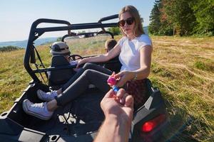 excited people having fun enjoying beautiful sunny day holding colorful torches while driving a off road buggy car photo