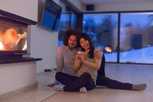 happy multiethnic couple sitting in front of fireplace photo