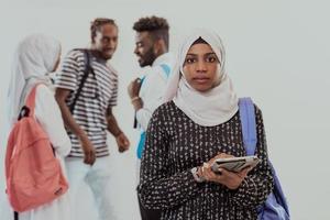 African female student with group of friends in background wearing traditional Islamic hijab clothes. Selectve focus photo