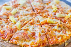 La pizza hawaiana es una comida italiana que se prepara con salsa de tomate, piña picada, jamón y queso. foto