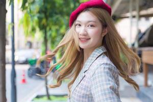 Asian beautifu lady with bronze hair wears red cap and turns to face on the street background. photo