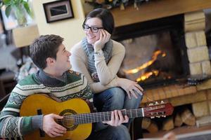 Young romantic couple sitting and relaxing in front of fireplace at home photo