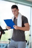 entrenador con portapapeles de pie en un gimnasio brillante foto