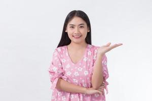 Asian woman in pink dress shows her hand to present something on white background. photo