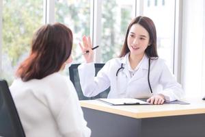 Asian doctor woman who wears medical coat talks with woman patient elderly to suggest treatment guideline and healthcare concept in office photo