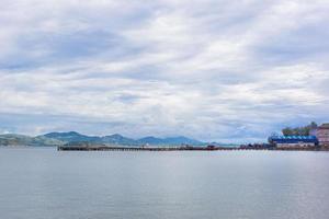 The sea view and port with sky is full of clouds. There is mountain on background. photo