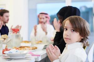 little muslim boy praying with family before iftar dinner photo