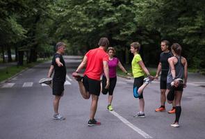 runners team warming up and stretching before morning training photo