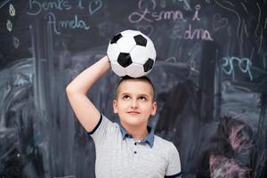 happy boy holding a soccer ball on his head photo