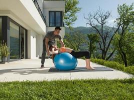 woman and personal trainer doing exercise with pilates ball photo