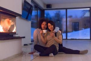 happy multiethnic couple sitting in front of fireplace photo