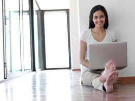 relaxed young woman at home working on laptop computer photo