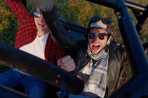 two young happy excited men enjoying beautiful sunny day while driving a off road buggy car photo