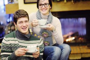 Young romantic couple sitting and relaxing in front of fireplace at home photo