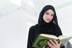 joven musulmana leyendo el corán en casa foto
