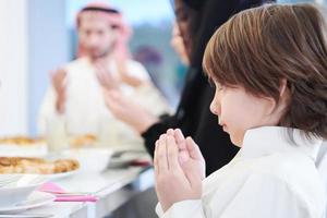 little muslim boy praying with family before iftar dinner photo