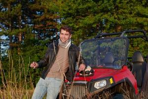 man enjoying beautiful sunny day smoking a cigarette while taking a break from driving a off road buggy car photo