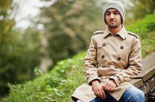 Stylish kuwaiti man at trench coat and hat. photo