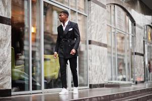 Portrait of young and handsome african american businessman in suit and white sneakers. photo