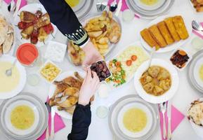 Muslim family having Iftar dinner eating dates to break feast top view photo