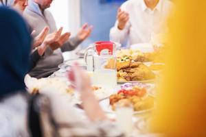 modern multiethnic muslim family praying before having iftar dinner photo