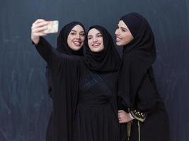 muslim women taking selfie picture in front of black chalkboard photo