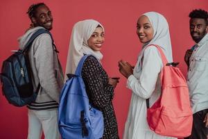 A group of African Muslim students with backpacks posing on a pink background. the concept of school education. photo