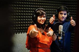 Young asian duet singers with microphone recording song in record music studio. photo