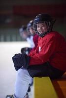 niños jugadores de hockey sobre hielo en un banco foto