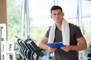 entrenador con portapapeles de pie en un gimnasio brillante foto