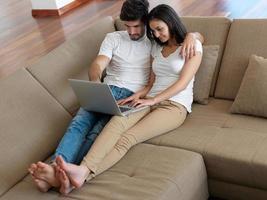 relaxed young couple working on laptop computer at home photo