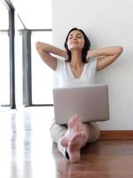 relaxed young woman at home working on laptop computer photo