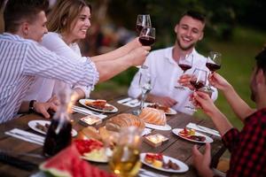 happy friends toasting red wine glass during french dinner party outdoor photo