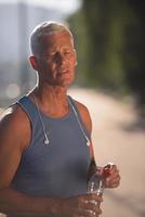 senior jogging man drinking fresh water from bottle photo