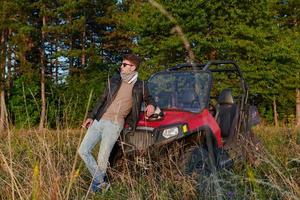 man enjoying beautiful sunny day smoking a cigarette while taking a break from driving a off road buggy car photo