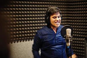 joven cantante asiático con micrófono grabando una canción en un estudio de grabación de música. foto