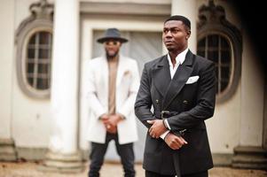 dos hombres negros de moda. retrato de moda de modelos masculinos afroamericanos. llevar traje, abrigo y sombrero. foto