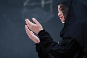 mujer musulmana haciendo oración tradicional a dios frente a pizarra negra foto
