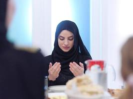 muslim woman making traditional prayer to God before iftar dinner with family photo