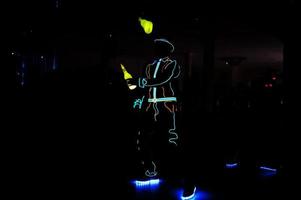 Professional barman and led light show. Silhouette of modern bartender shaking drink at night cocktail bar. photo