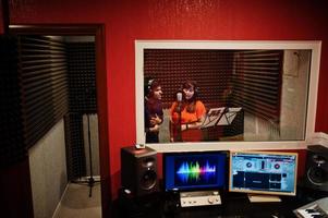 Young asian duet singers with microphone recording song in record music studio. photo