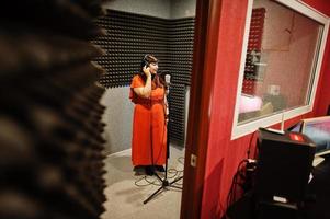 Young asian singer with microphone recording song in record music studio. photo