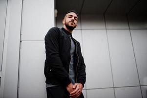 Portrait of stylish arab beard man wear grey turtleneck and black jaket. Arabian model guy against steel wall. photo